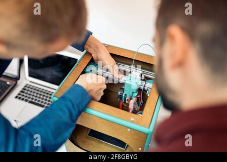 Stock photo of unrecognized technicians fixing modern 3d printer. Stock Photo