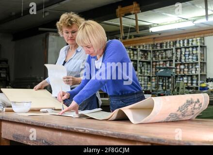 Berlin, Germany. 13th Apr, 2021. Assortment bookbinder Frauke Grenz (l) and bookbinder Julia Flögel work on restoring a Chinese scroll painting in their paper workshop in Friedrichshagen. Here they repair a wide variety of damage to books, letters, documents, maps, travel cases, boxes as well as pictures. They also produce books as unique pieces or in smaller editions and offer numerous courses. The shop is located in an old print shop with old drawers full of metal type, as well as machines for embossing, cutting and binding. Credit: Jens Kalaene/dpa-Zentralbild/ZB/dpa/Alamy Live News Stock Photo