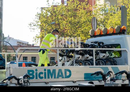 MADRID, SPAIN - Apr 06, 2021: Operators of the BiciMAD bicycle rental service in Madrid, loading a small truck with some bicycles to transport them to Stock Photo