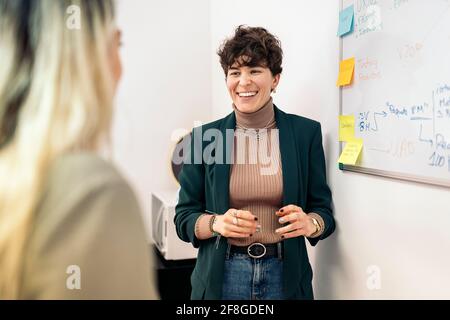 Happy business woman talking with her coworker during work reunion. Stock Photo