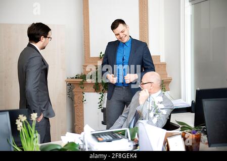Three Male Architects Chatting In Modern Office Together Stock Photo