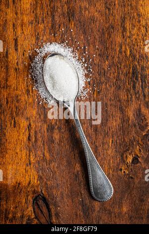 White sugar in spoon on wooden table. Top view. Stock Photo