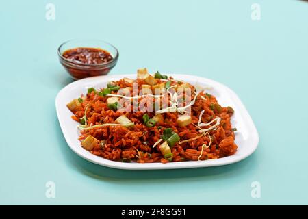 Schezwan paneer fried rice with schezwan sauce, Chinese fried rice with paneer, garnished with spring onion and cabbage Stock Photo