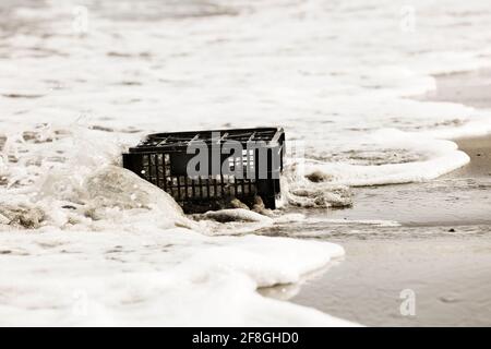black plastic box thrown on the shore, environmental pollution, Stock Photo