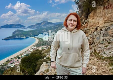 Lycian Trail in Blue Lagoon area of Oludeniz village near Fethiye, young white woman with red hair poses against backdrop of landscape. Stock Photo