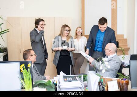 Business people are using gadgets, drinking coffee, talking and smiling while working in modern office Stock Photo