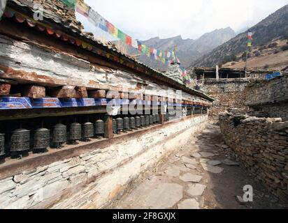 Buddhist prayer many wall with prayer wheels in nepalese village, round Annapurna circuit trekking route, Nepal Stock Photo