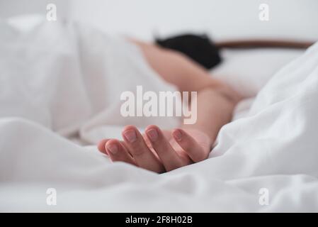 Close-up of a man's hand upside down on the bed while sleeping. Stock Photo
