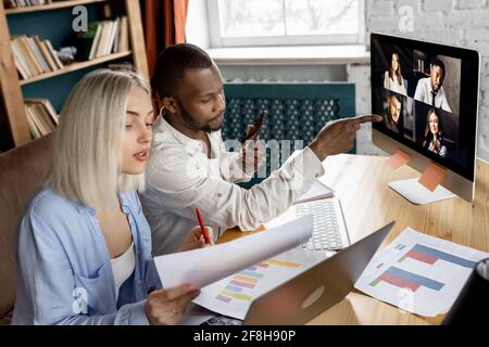 Serious multiracial business partners having online briefing meeting, discussing new strategy. Concentrated colleagues learning financial graphs Stock Photo