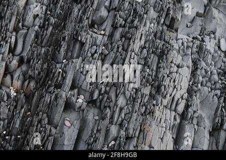 Gray striped rock. Texture natural minimalistic stone background. Parallel striped lines of mountain close up. Stock Photo