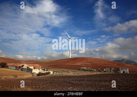 Spain, Andalusia, Wind turbine in front and rundown houses, farm Stock Photo