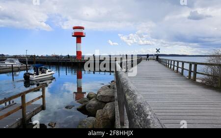Schleswig-Holstein, Eckernförde: 14 April 2021,  Only a few people are on the jetty in the harbour at the lighthouse at the tip of the harbour. Photo: Christian Charisius/dpa Stock Photo