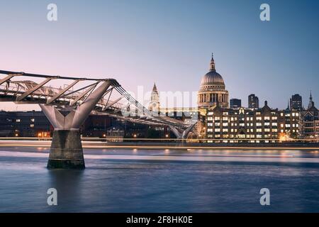 London cityscape at dusk. City waterfront with Millennium Footbridge against St. Pauls Cathedral. United Kingdom.