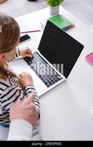 cropped view of schoolgirl near laptop with blank screen and father at home Stock Photo
