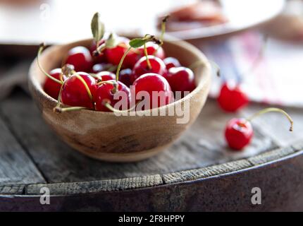 small wooden bowl of bright red cherries with back light Stock Photo