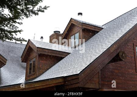 Top of a house made of wood under a thin layer of snow in fall and snow falling Stock Photo