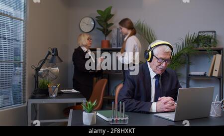 Happy senior business man entrepreneur working on laptop listening music on headphones Stock Photo