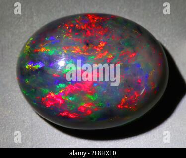 Natural gemstone black opal on gray background Stock Photo