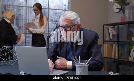 Senior freelancer concentrated developing project while working, typing on laptop computer in office Stock Photo