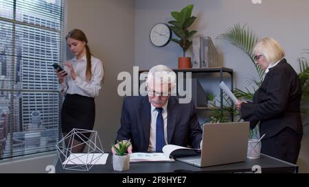 Senior freelancer concentrated developing project while working, typing on laptop computer in office Stock Photo