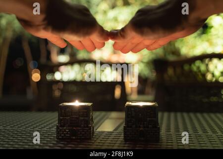 Hands of man above candles praying on friday night dinner for popular Shabbat meal. Jewish day of rest tradition with bokeh light effect on background Stock Photo