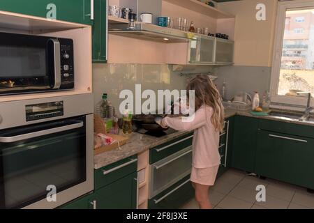 little girl in huge green kitchen preparing pancakes