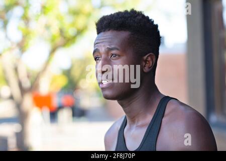 A handsome young black man stands in a street with defocused background on sunny afternoon Stock Photo