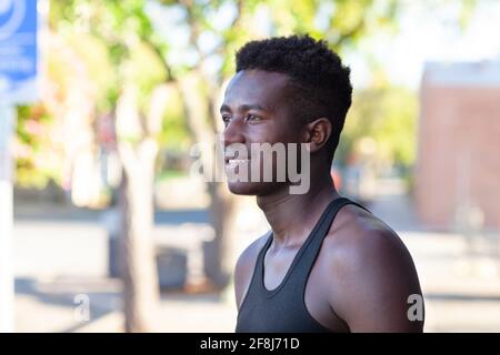 A handsome young black man stands in a street with defocused background on sunny afternoon Stock Photo