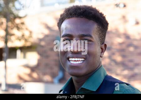 A handsome smiling young black student stands in front of his college Stock Photo