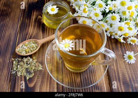 Tea in the glass cup with chamomile and honey on the brown wooden background Stock Photo