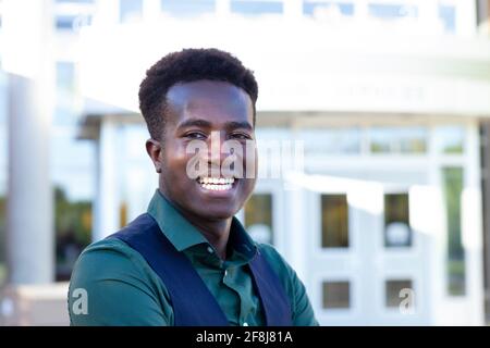 A handsome smiling young black student stands in front of his college Stock Photo