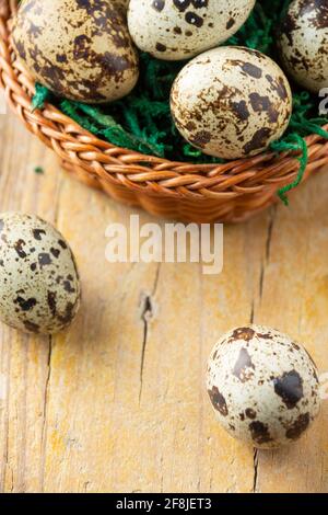 Top view of basket with quail eggs on wooden table with two eggs, selective focus, vertical, with copy space Stock Photo