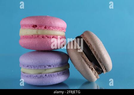 three macaroons lie triangle on a blue background with a place for text and copyspace. Stock Photo