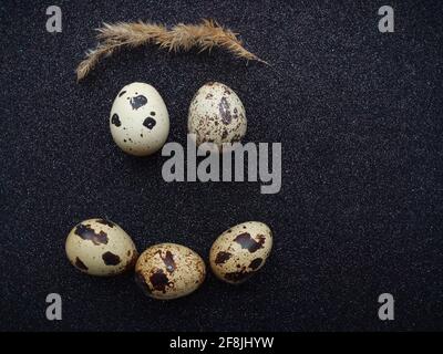 five quail eggs in the form of a smile on a black background closeup Stock Photo