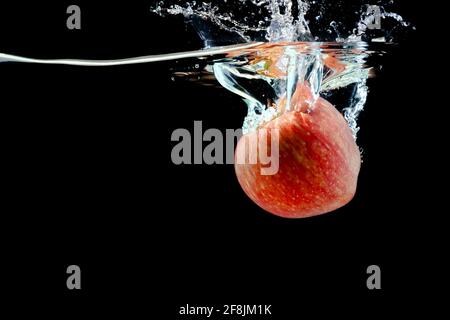 ripe red apple fell into the water with splashes Stock Photo