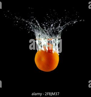 tangerine in water on a black background, place under the text Stock Photo