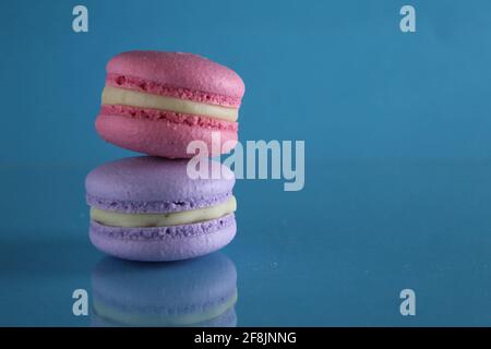 three macaroons lie triangle on a blue background with a place for text and copyspace. Stock Photo