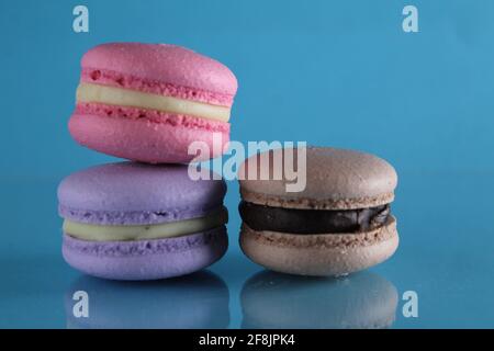 three macaroons lie triangle on a blue background with a place for text and copyspace. Stock Photo