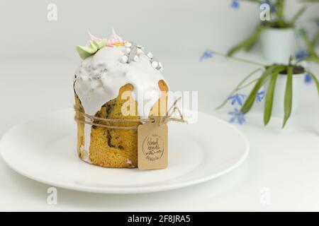 Orthodox Easter cake with white fondant and marshmallows tied with a rope on a plate with spring flowers in a pot Stock Photo