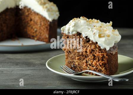 A home baked gluten free carrot and walnut cake. This moist cake has an indulgent cream cheese topping and was made with gluten free ingredients Stock Photo