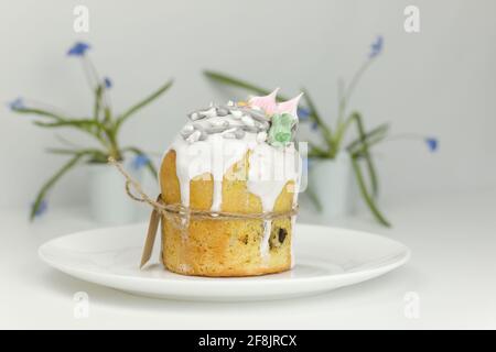 Orthodox Easter cake with white fondant and marshmallows tied with a rope on a plate with spring flowers in a pot Stock Photo