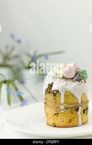Orthodox Easter cake with white fondant and marshmallows tied with a rope on a plate with spring flowers in a pot Stock Photo