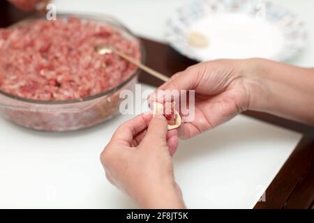 A housewife is cooking pelmeni at home Stock Photo