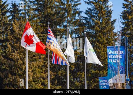 Canadian, British Columbian, First Nations, and the Whistler village flags blowing in the wind in Whistler Village British Columbia Canada