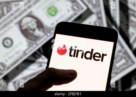 In this photo illustration, the mobile dating app Tinder logo is seen on an Android mobile device screen with the currency of the United States dollar icon, $ icon symbol in the background. Stock Photo