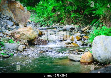 View enroute to Prashar Lake trekk trail through small waterfall rivulet. It is located at a height of 2730 m above sea level surrounded by lesser him Stock Photo