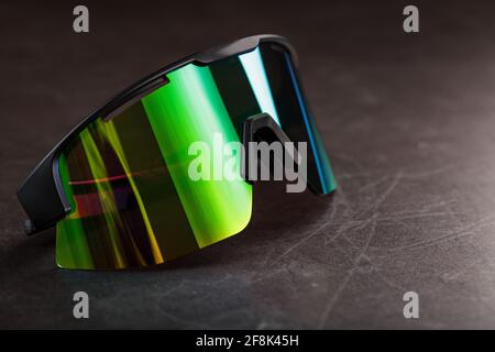 Sports glasses with a green mirrored lens on a black textured background. Free space. Stock Photo