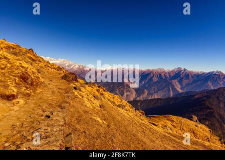 This is the view enroute to Khalia top trek trail through Himalayas autumn alpine grass landscape at Munsiyari. Khalia top is at an altitude of 3500m Stock Photo