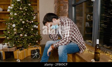 Problems of alcoholism in loneliness, sadness and melancholy during pandemic covid 19. Male removes mask from coronavirus, drinking wine from bottle Stock Photo