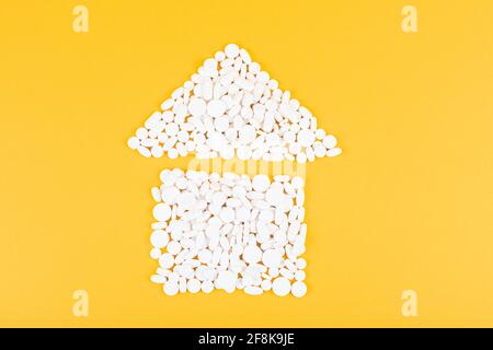 The house shape made of pills on yellow background. Medicine and healthcare concept. Pharmacy concept. Flat lay. Copy space. Stock Photo